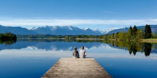 Kinder auf Steg in See mit Bergpanorama