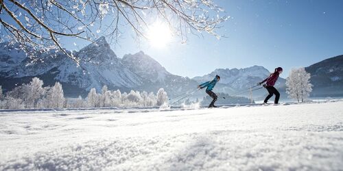 Zwei Langlauf Skifahrer in der Zugspitzarena mit Bergpanorama im Hintergrund