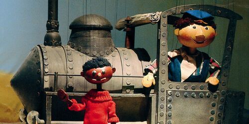 Figuren der Augsburger Puppenkiste vor Spielzeuglokomotive