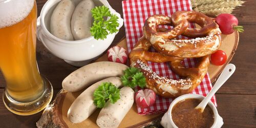 Tisch mit Bier, Weißwurst, Senf und Brezeln