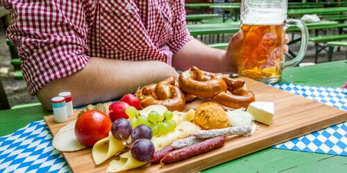 Mann mit kariertem Hemd, Mass Bier und gedecktem Frühstücksbrettchen