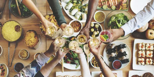 Tisch mit Essen und Menschen, die sich zuprosten