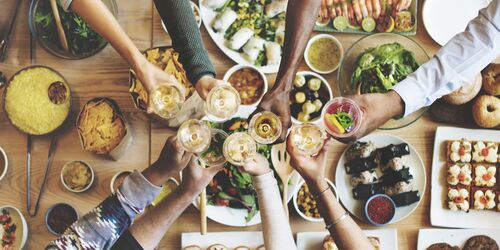 Tisch mit Essen und Menschen, die sich zuprosten